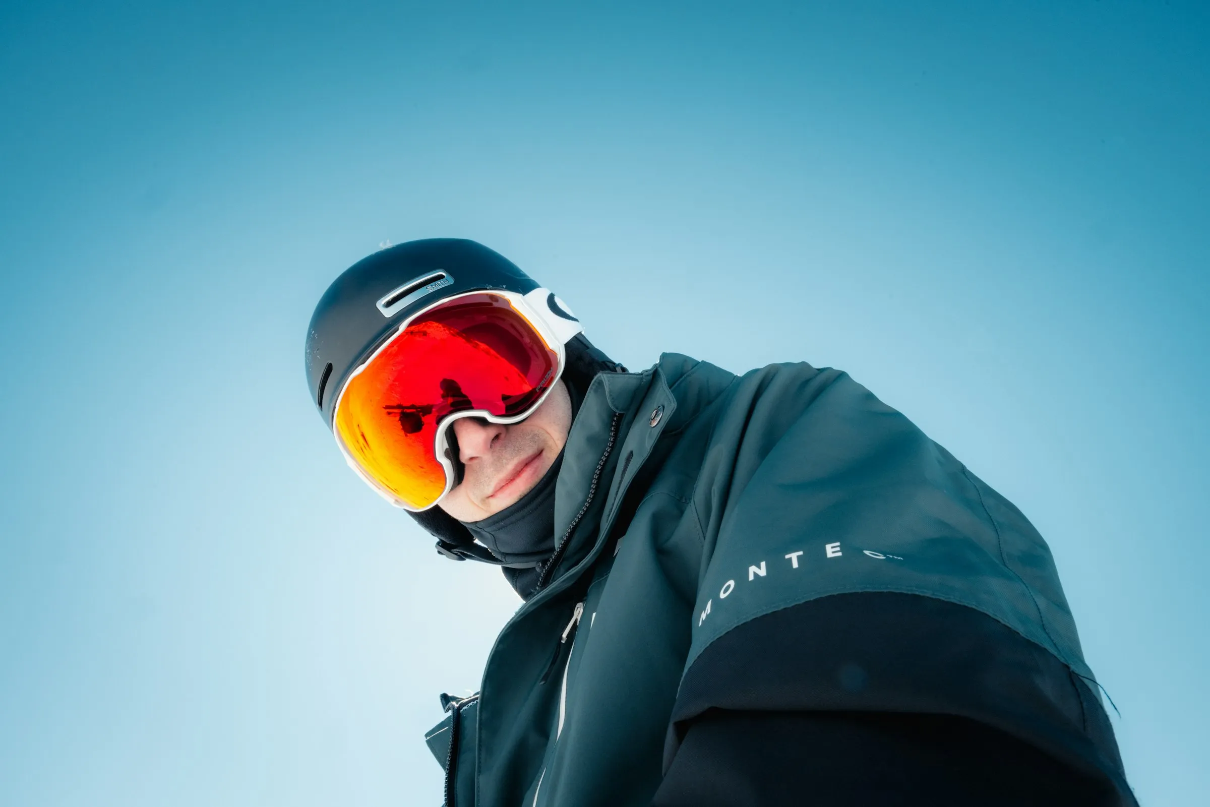 戴安全帽、雪鏡與脖圍,穿著滑雪外套的單板玩家